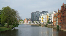 Footbridge Over The River Great Ouse At Bedford With Trees And Modern Buildings.