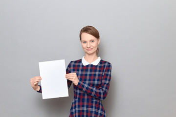 Studio portrait of happy young woman holding white blank paper sheet