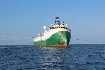 Wall Mural - Seismic survey vessel moving ahead with all towed in sea equipment deployed. Oil and gas exploration. Restricted manoeuvrability day signals hoisted.