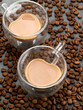 Two glass cups in form of heart with coffee on coffee beans background.