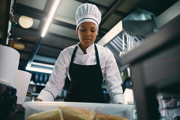 Wall Mural - Black female chef assistant works in the kitchen.