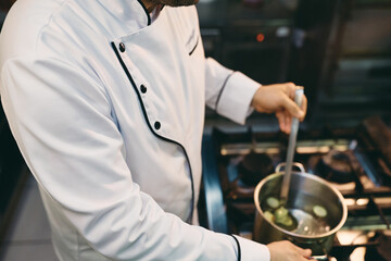 Wall Mural - Unrecognizable chef cooking while working in kitchen at restaurant.