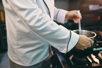 Wall Mural - Close up of chef preparing meal while working in kitchen at restaurant.