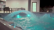 Close-up Of A Modern Hot Tub For Relaxation Therapy And Rehabilitation In A Hotel. The Jet Of Water In The Bath Falls. In The Evening On The Street With Illumination