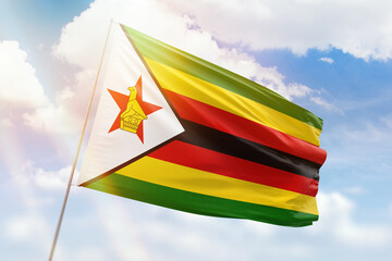 Wall Mural - Sunny blue sky and a flagpole with the flag of zimbabwe