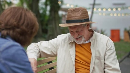 Wall Mural - Happy senior couple sitting on bench and talking outdoors in town.