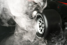 Modern Racing Car With Smoke From Under Wheels On Dark Background, Closeup