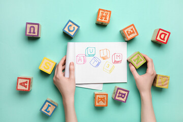 Female hands, notebook with word AUTISM and cubes on color background