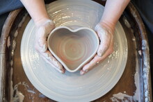 Women Hands On A Potter  Wheel Sculpt A Pot In The Shape Of A Heart
