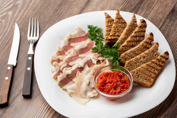 Raw chopped pork lard with meat, a head of garlic and rye bread on a wooden background for copy space. A large chunk of fresh fat.