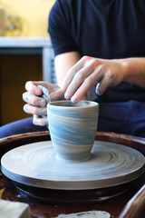 Wall Mural - Close-up of male potter hands molding clay in pottery workshop.