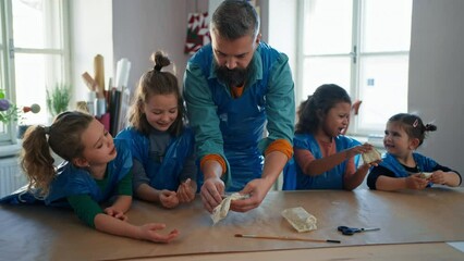 Wall Mural - Group of little kids with teacher working with pottery clay during creative art and craft class at school.