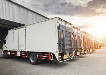 Wall Mural - Row of Cargo Container Trucks Parked Lot at Distribution Warehouse with the Sunset. Shipping Container Lifting Ramp Trucks. Lorry. Cargo Freight Trucks Transport Logistics.	