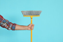 Man With Yellow Broom On Light Blue Background, Closeup