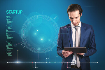 Poster - Attractive young european businessman using tablet with futuristic blue HUD interface and glowing programming code on blurry blue background. Digital start up, future and technology concept.