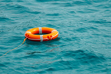 Orange Lifebuoy Floating On Blue Sea Water