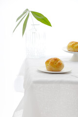 Poster - Scenic shot of homemade fresh bread on a plate on the table in a full white interior