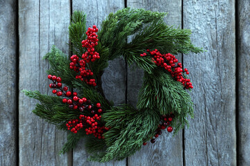 Poster - Beautiful Christmas wreath with red berries hanging on wooden wall