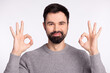 © Tetiana - Photo of young handsome man show fingers okey symbol choice advertise isolated over grey color background