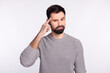 © Tetiana - Photo of brunet man finger touch head wear grey jumper thinking minded isolated on grey color background