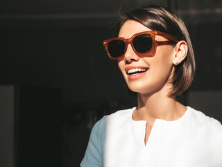 Closeup portrait of young beautiful smiling female. Sexy carefree woman posing at sunny day on dark background. Positive model having fun and going crazy. Cheerful and happy. In sunglasses