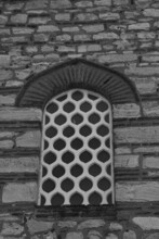 Black And White Photography. A Window With An Openwork White Lattice In The Wall Of An Old Stone Building.