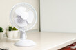 A small fan on the kitchen table. The concept of cooling and ventilation of the house. Copy space