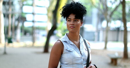 Pensive young black woman standing outside thinking