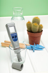 pH meter in glass of water, and plant cactus with tools bottle on a white background. Measurement of the characteristics of drinking water. The hardness of the water. Drinking water quality 