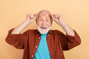 Wall Mural - Photo of impressed elder grey hairdo man look camera wear spectacles brown shirt isolated on beige color background