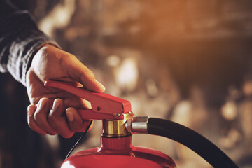 hand presses the trigger fire extinguisher available in fire emergencies conflagration damage background. Safety