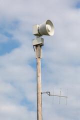 Load speaker / siren on a pole with cloudy sky in the background