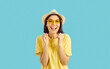 Cheerful beautiful young woman getting excited in anticipation of summer holiday trip. Happy pretty girl in yellow T shirt and hat isolated on blue background looking at camera, smiling and laughing