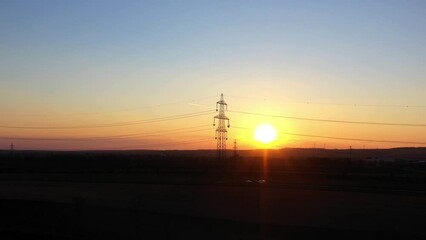 Wall Mural - Golden Hour Sunset With Electricity Pylon In Silhouette Against Sunlit Background. wide zoom-in