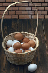 Poster - a lot of fresh chicken eggs in a straw basket on a dark wooden background. Healthy eating concept