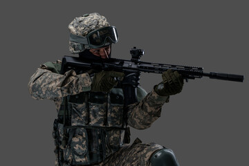 Wall Mural - Shot of serviceman dressed in protective helmet and uniform aiming rifle.