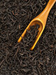 dry black tea leavs background and wooden spoon