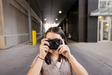 Portrait Girl Aiming Digital Camera In Urban Alley
