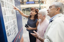 Senior Couple And Daughter Looking At Information Board In City