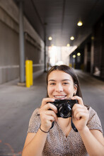 Portrait Happy Girl With Braces Using Digital Camera In Urban Alley
