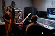 © pressmaster - Mature African American music producer and two young musicians discussing something in recording studio