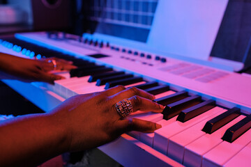 Poster - Close-up of unrecognizable Black womans hands playing electronic keyboard in blue and pink neon light