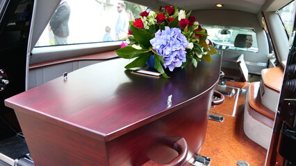 closeup shot of a funeral casket or coffin in a hearse or chapel or burial at cemetery
