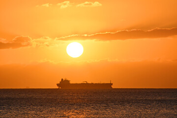 Sunset with cargo ship tanker on the horizon of the Pacific ocean