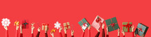 Many Hands With Christmas Gifts And Decorations On Red Background