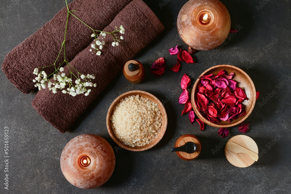 Beautiful spa composition with burning candles and rose petals on dark background