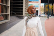 Smiling Muslim black woman in hijab standing near office building