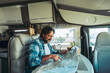 Nomadic traveler lifestyle adult mature man inside a camper van planning travel next destination on a paper map guide. Alternative home van life people enjoying freedom and living off grid. Vacation