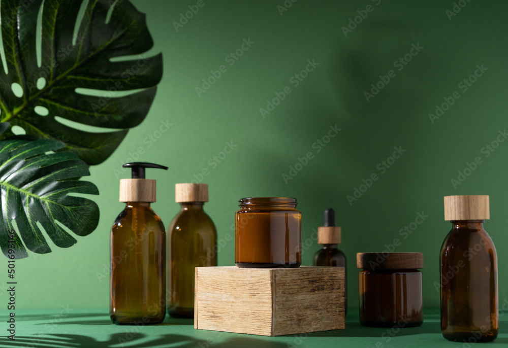 Bottles for cosmetics and cream on a pedestal, green background with ...