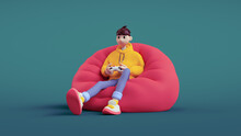Happy Positive Brunette Guy Wears A Yellow Hoodie, Blue Jeans Holds A White Gamepad In His Hands Plays Video Games Sitting On Red Bean Bag In Relaxed Pose. 3d Render In Minimal Style On Green Backdrop
